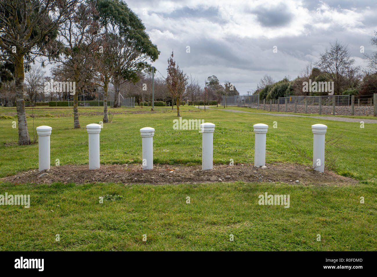 White plastic septic tank vents from public toilet facilities rise above the ground in a public