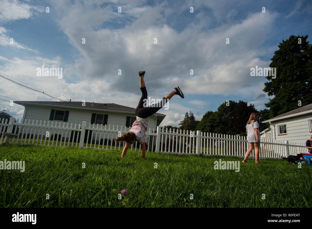 A young girls does a cartwheel in her family's backyard in the United States. Stock Photo
