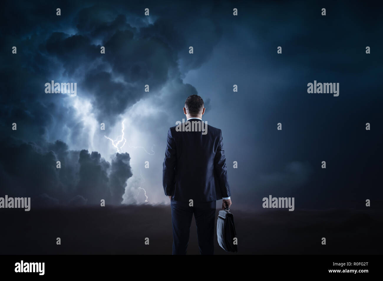 Trouble ahead, businessman standing in front of a stormy sky. Stock Photo