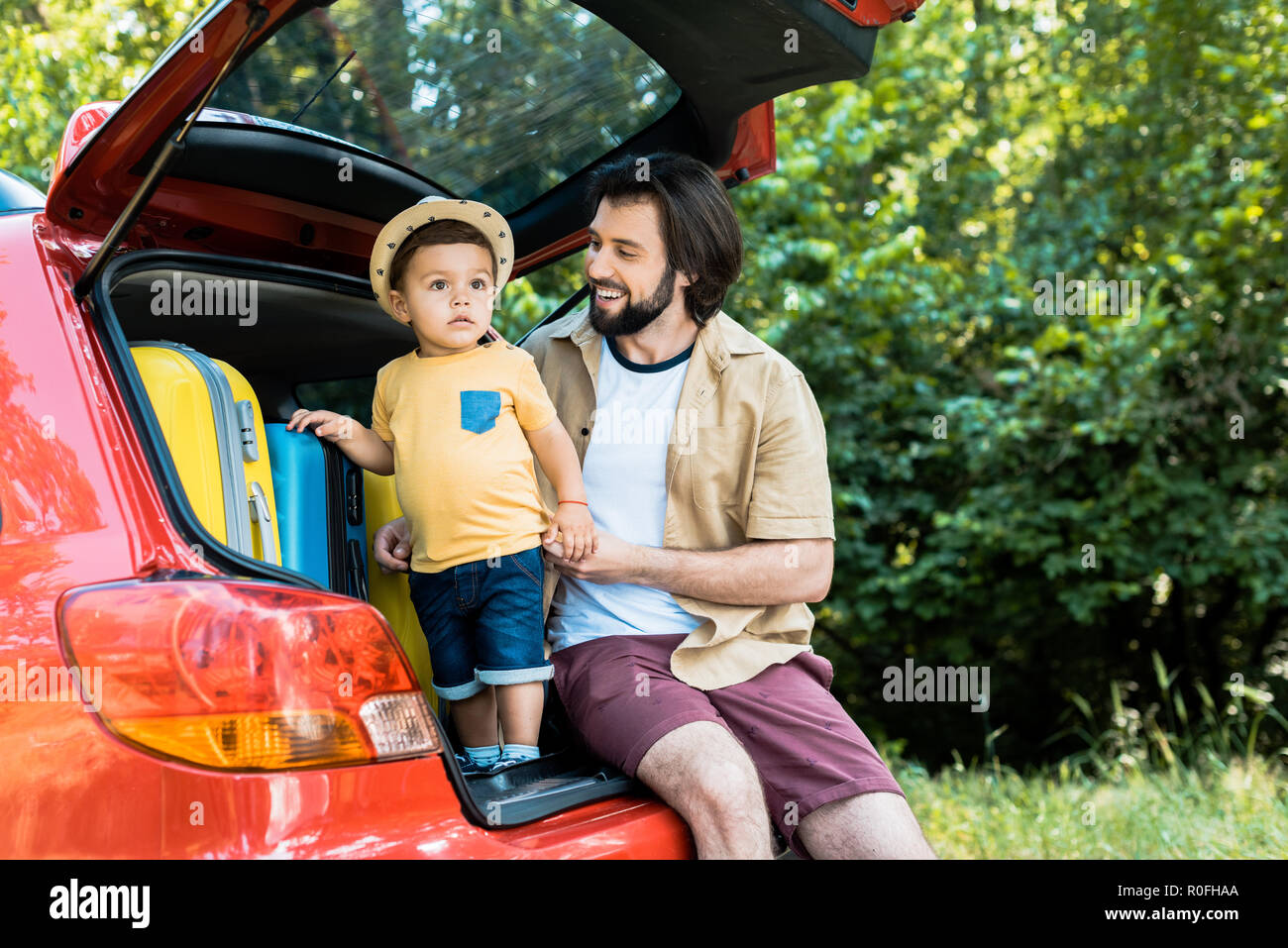 smiling father and son sitting on car trunk in forest Stock Photo - Alamy
