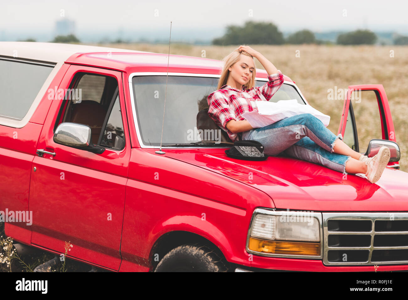 beautiful young woman relaxing on hood of car in field Stock Photo Alamy
