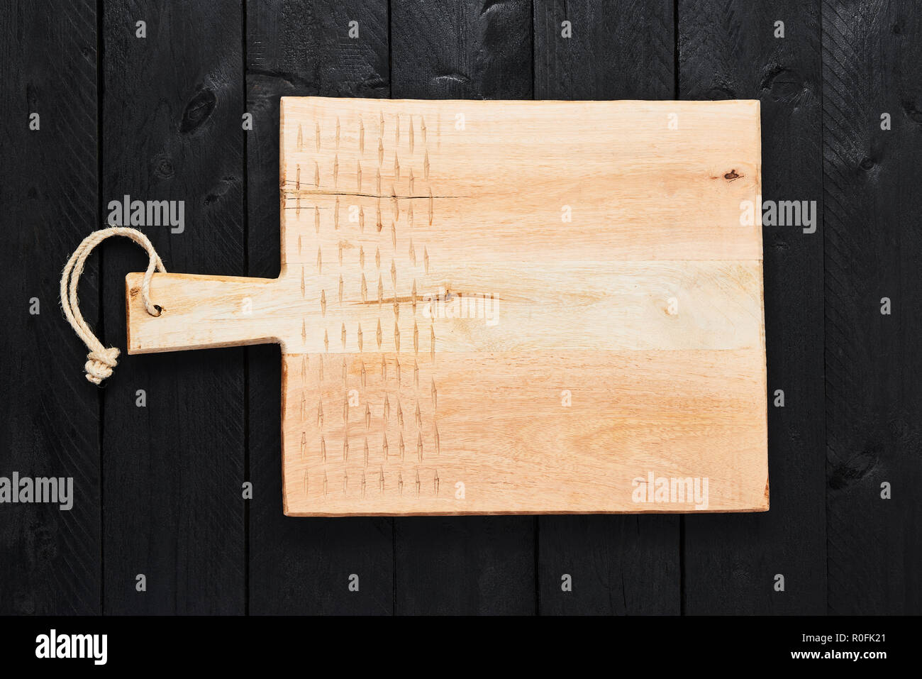 Top view of new handmade chopping board on black wooden table with copy space. Stock Photo