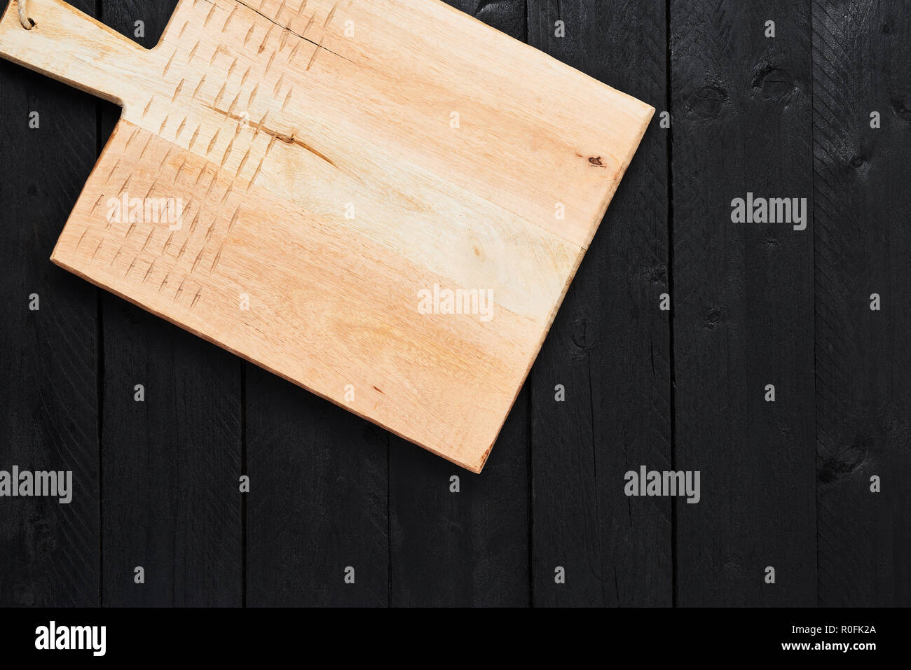 Top view of new handmade chopping board on black wooden table with copy space. Stock Photo