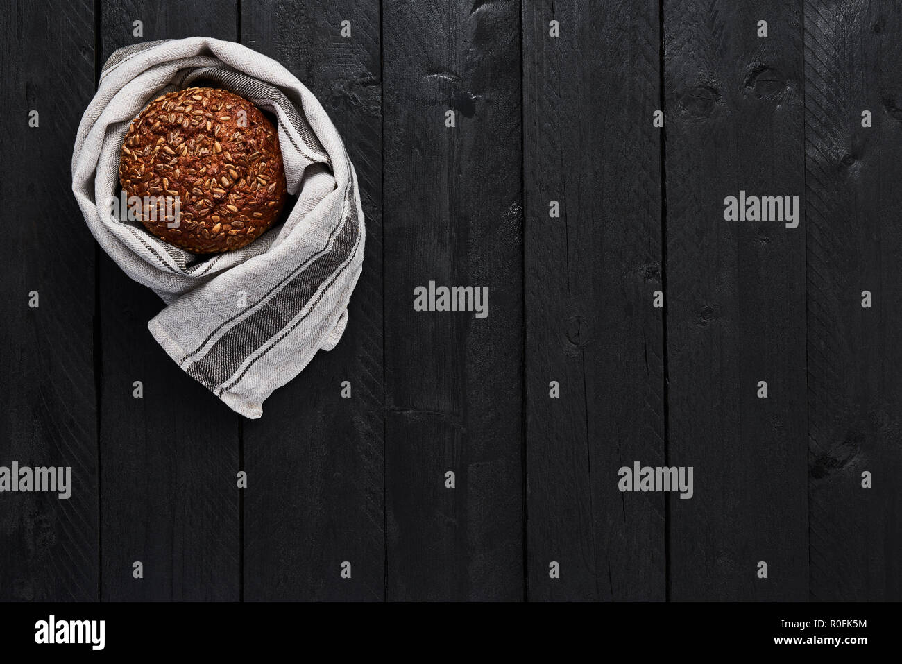 Whole wheat bread on black wooden table. Rustic food background concept. Top view. Stock Photo