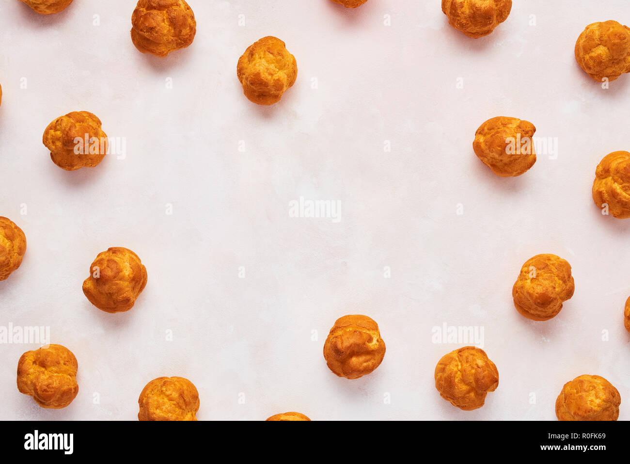 Assorted fresh cream puff cakes on rose background with copy space. Top view. Stock Photo