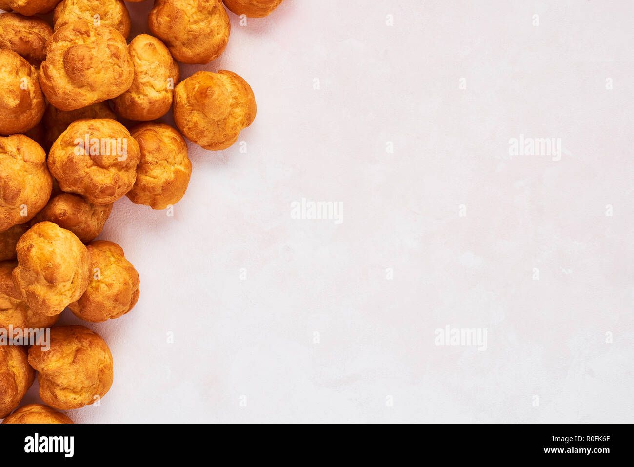 Bunch of fresh cream puff cakes on rose background with copy space. Top view. Stock Photo
