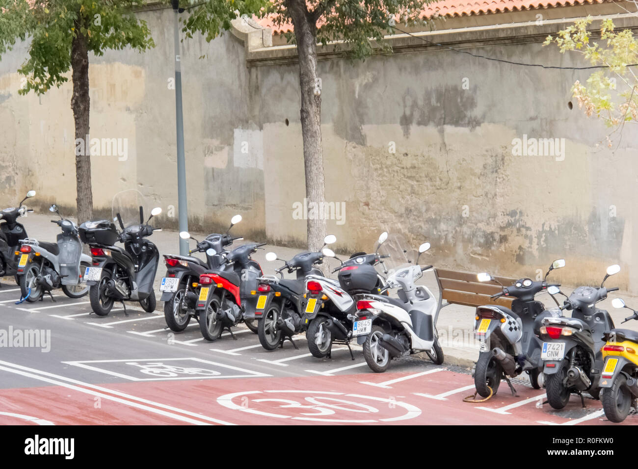 A row of mopeds, or motor scooters, parked in bays by the side of he