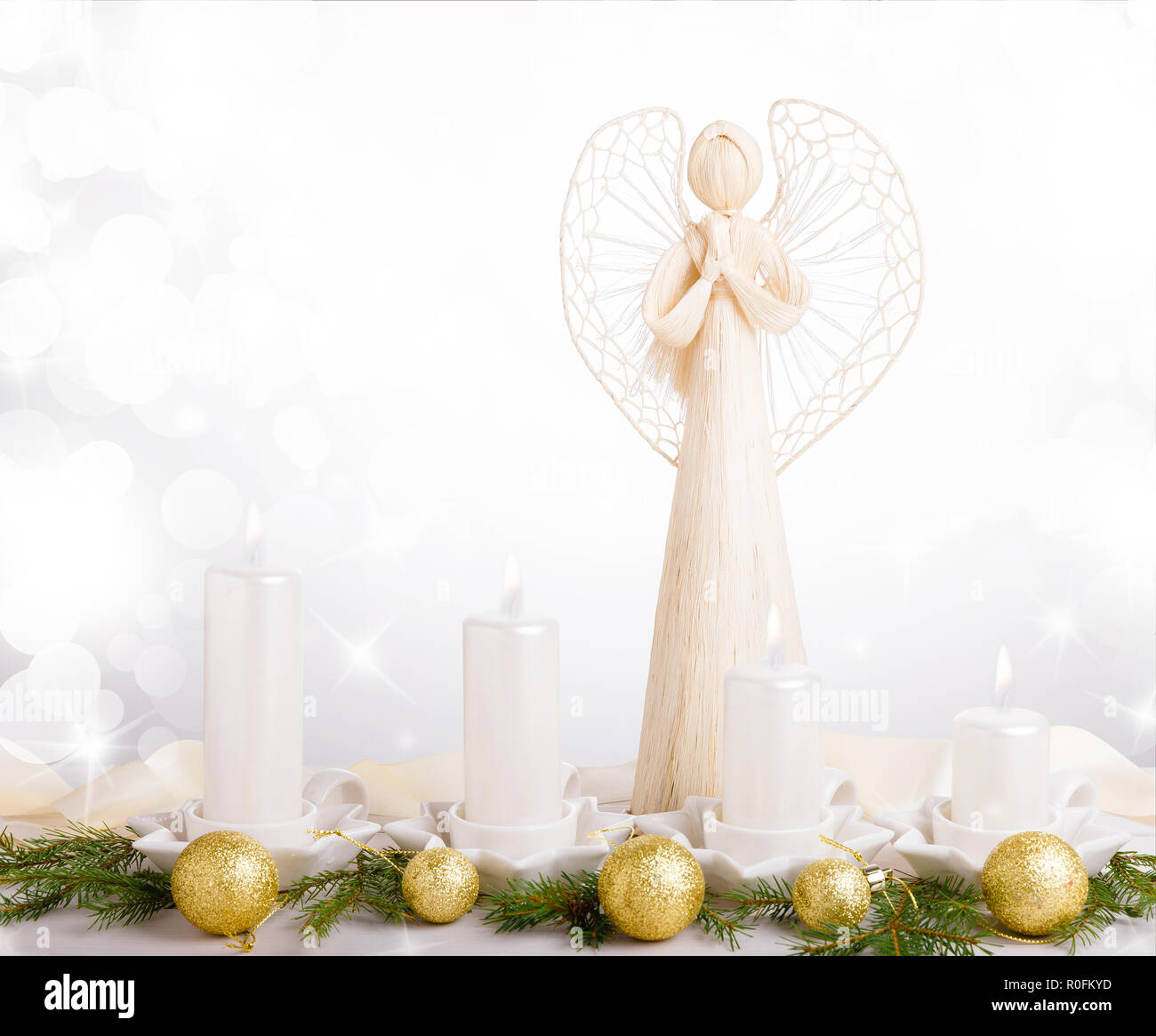 A white angel and four white Advent candles, Christmas tree branches are decorated with golden balls. Stock Photo