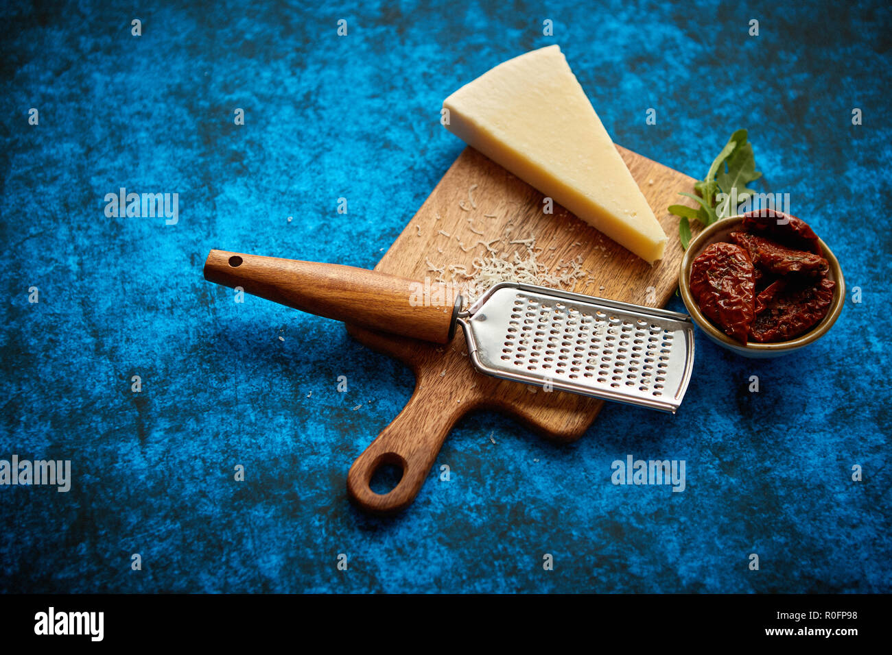 Grated parmesan cheese and metal classic grater placed on wooden