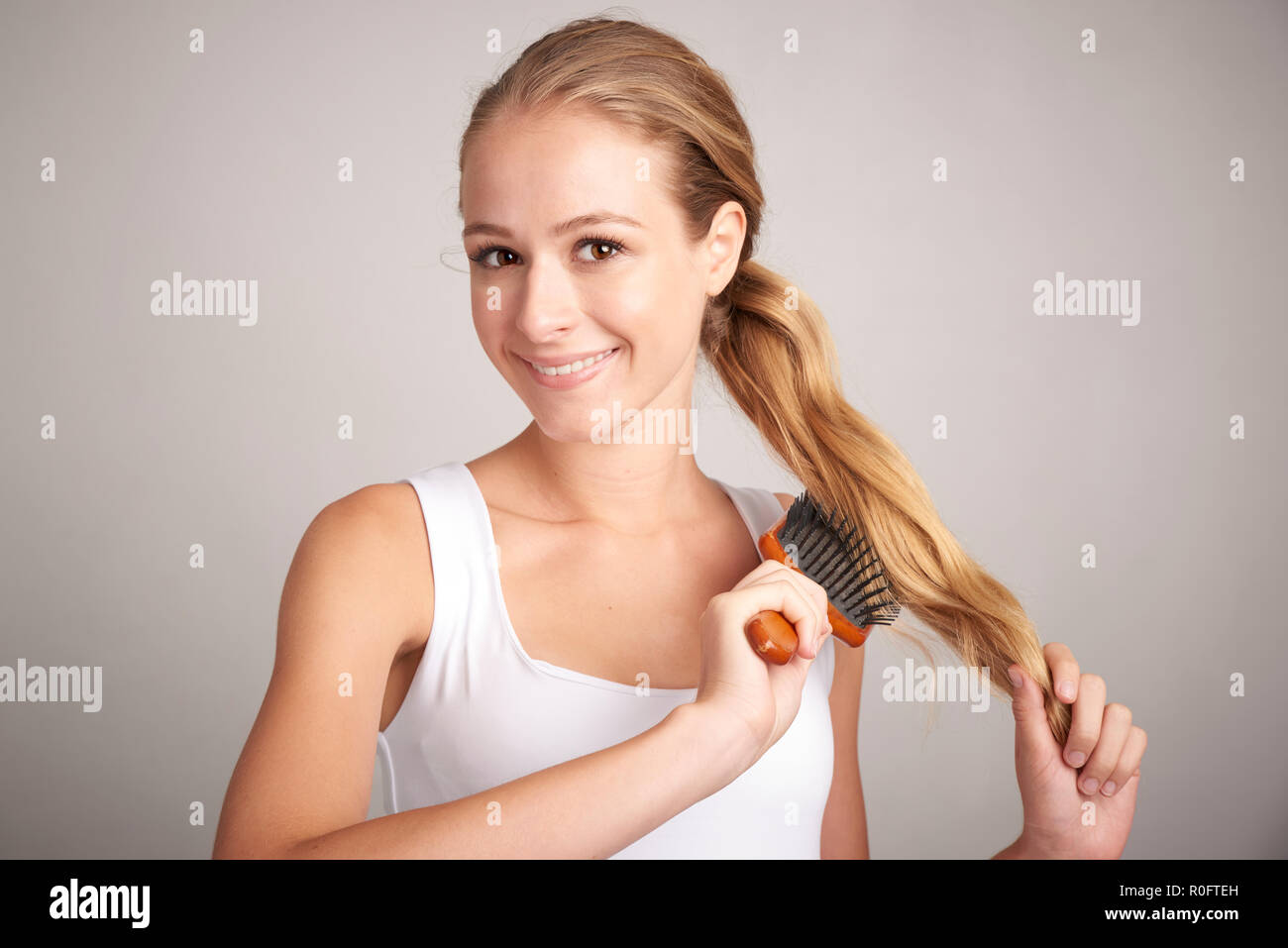 Portrait of attractive young woman brush her long blond hair while