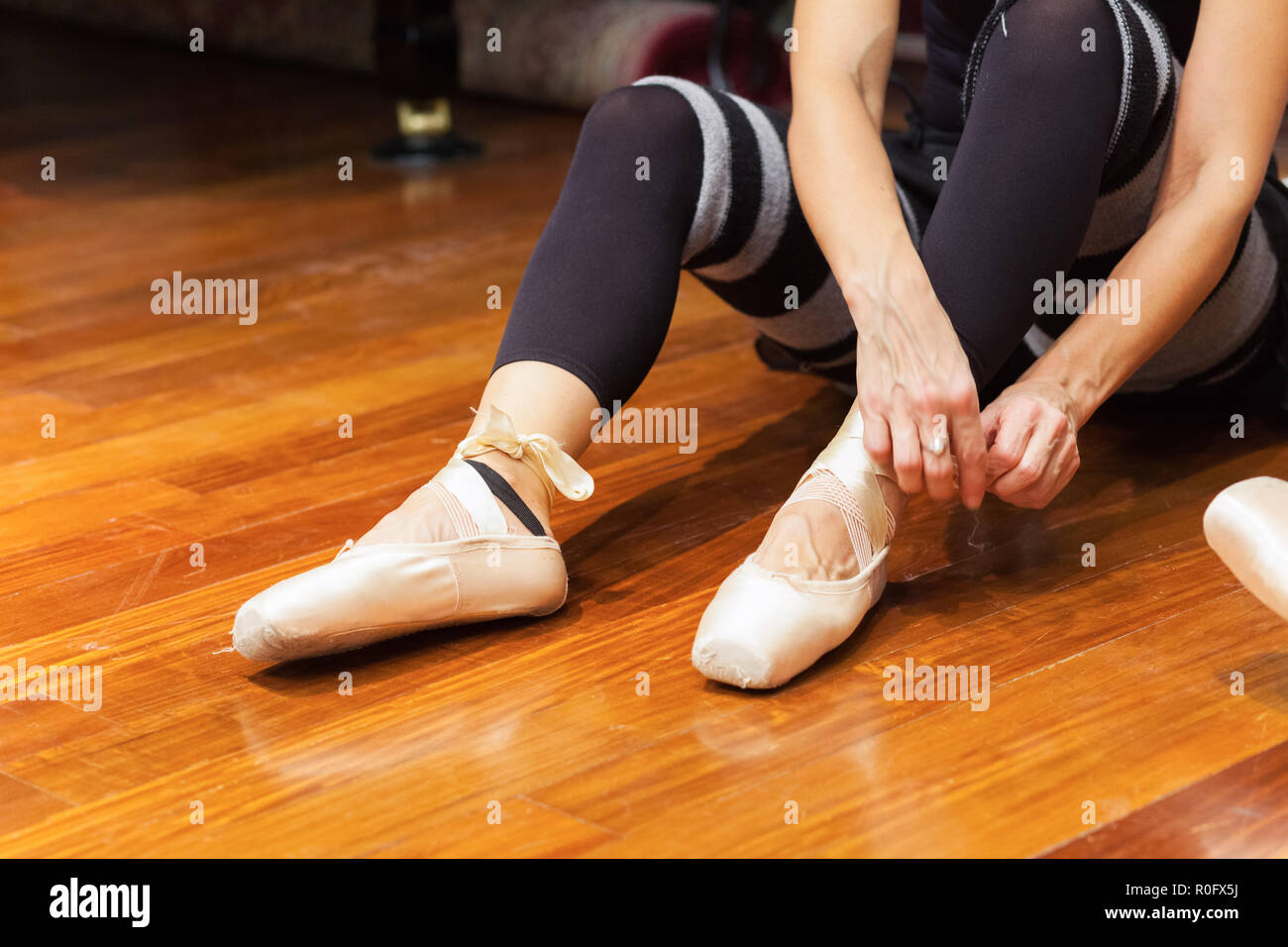 Classical dancer adjusting her shoes Stock Photo