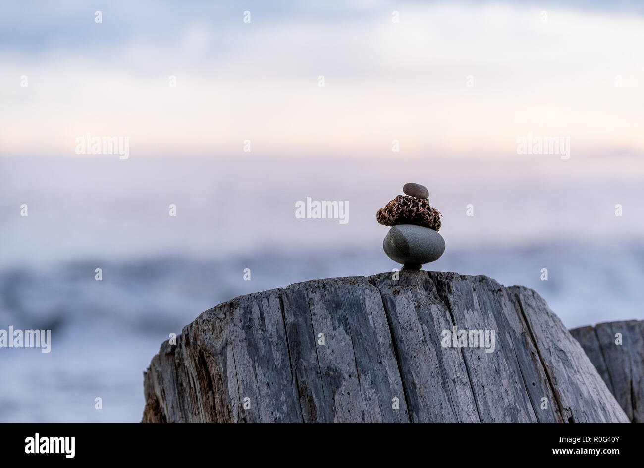 Balance and wellness concept. Close-up of ocean stones balanced on rocks and ocean driftwood. Low depth of field. Zen and spa inspired Stock Photo