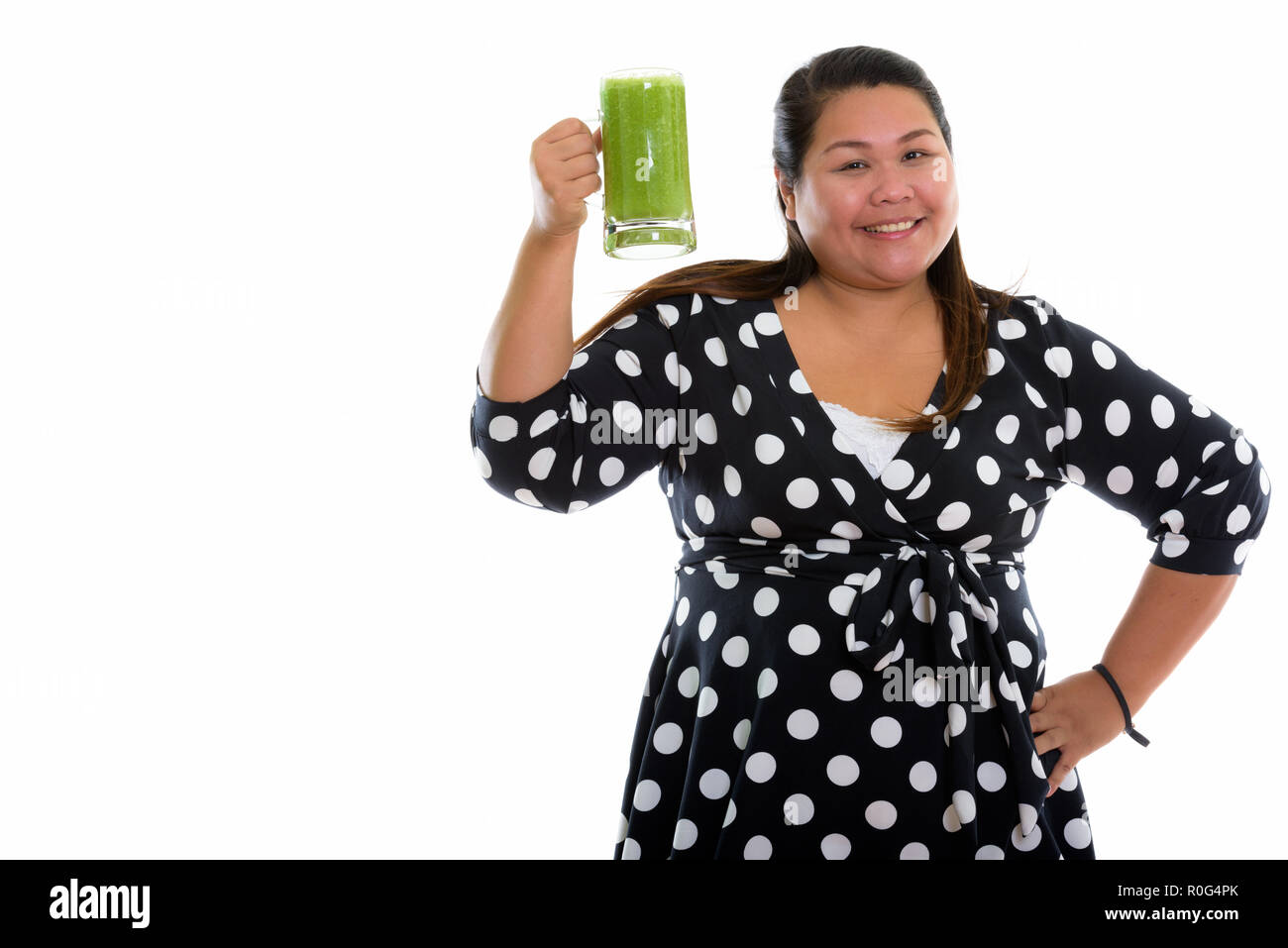 Studio shot of young happy fat Asian woman smiling while raising Stock Photo