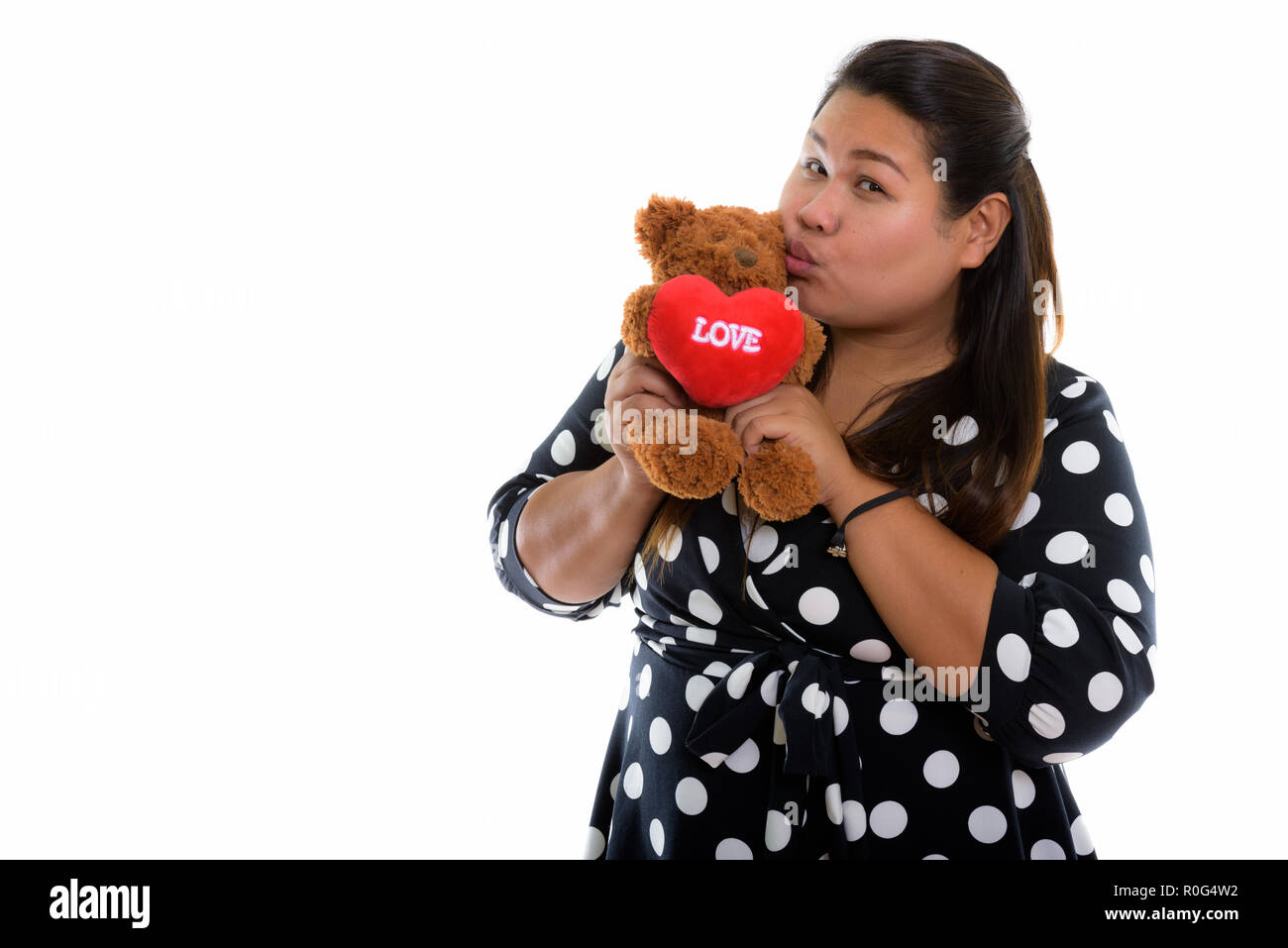 Studio shot of young fat Asian woman holding and kissing teddy b Stock Photo
