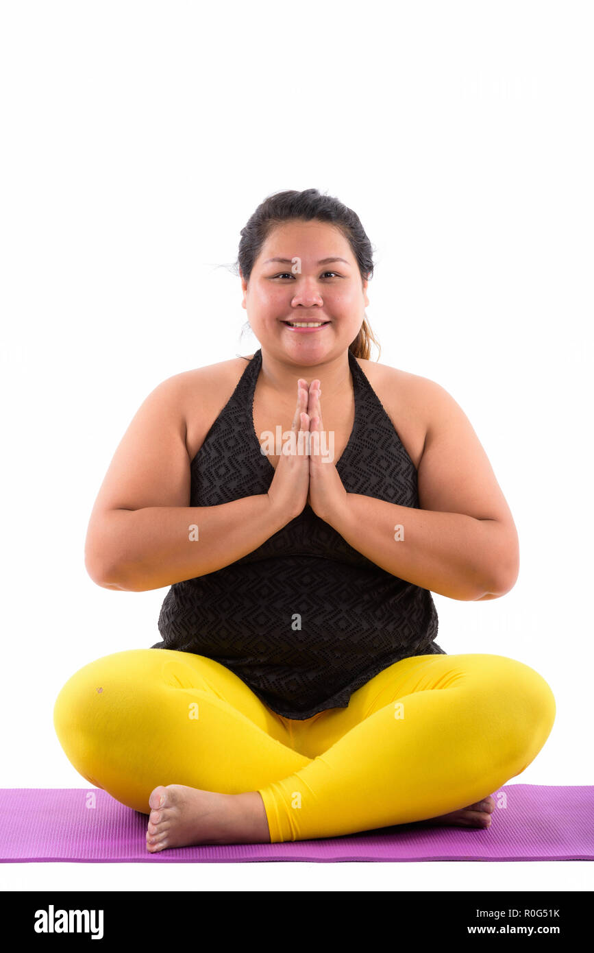 Studio shot of young happy fat Asian woman smiling and sitting w Stock Photo