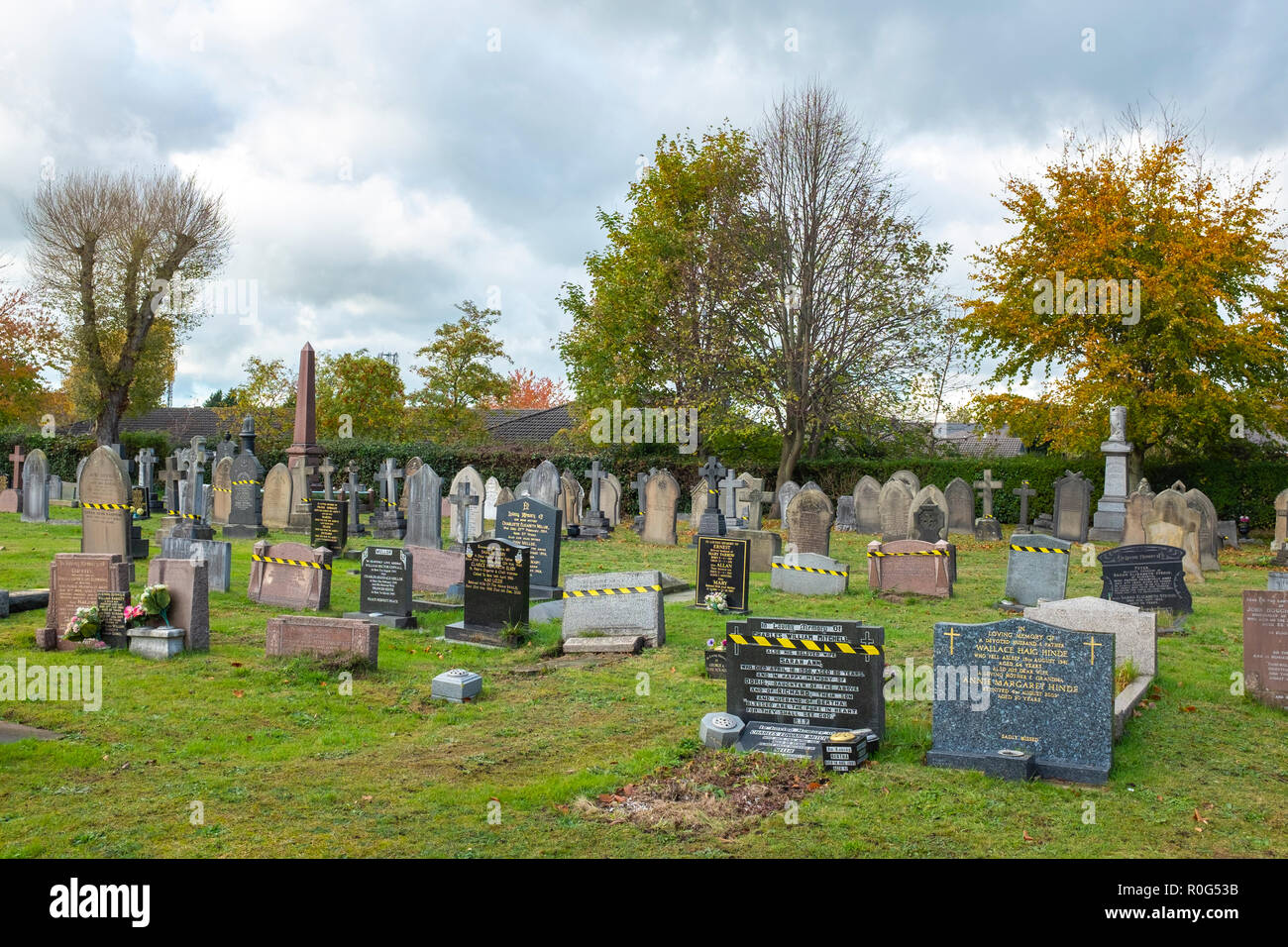 Headstones in danger of falling over protected by warning tape on a graveyard in Cheshire UK Stock Photo