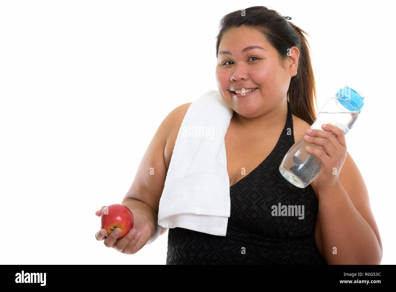 Studio shot of young happy fat Asian woman smiling while holding Stock Photo