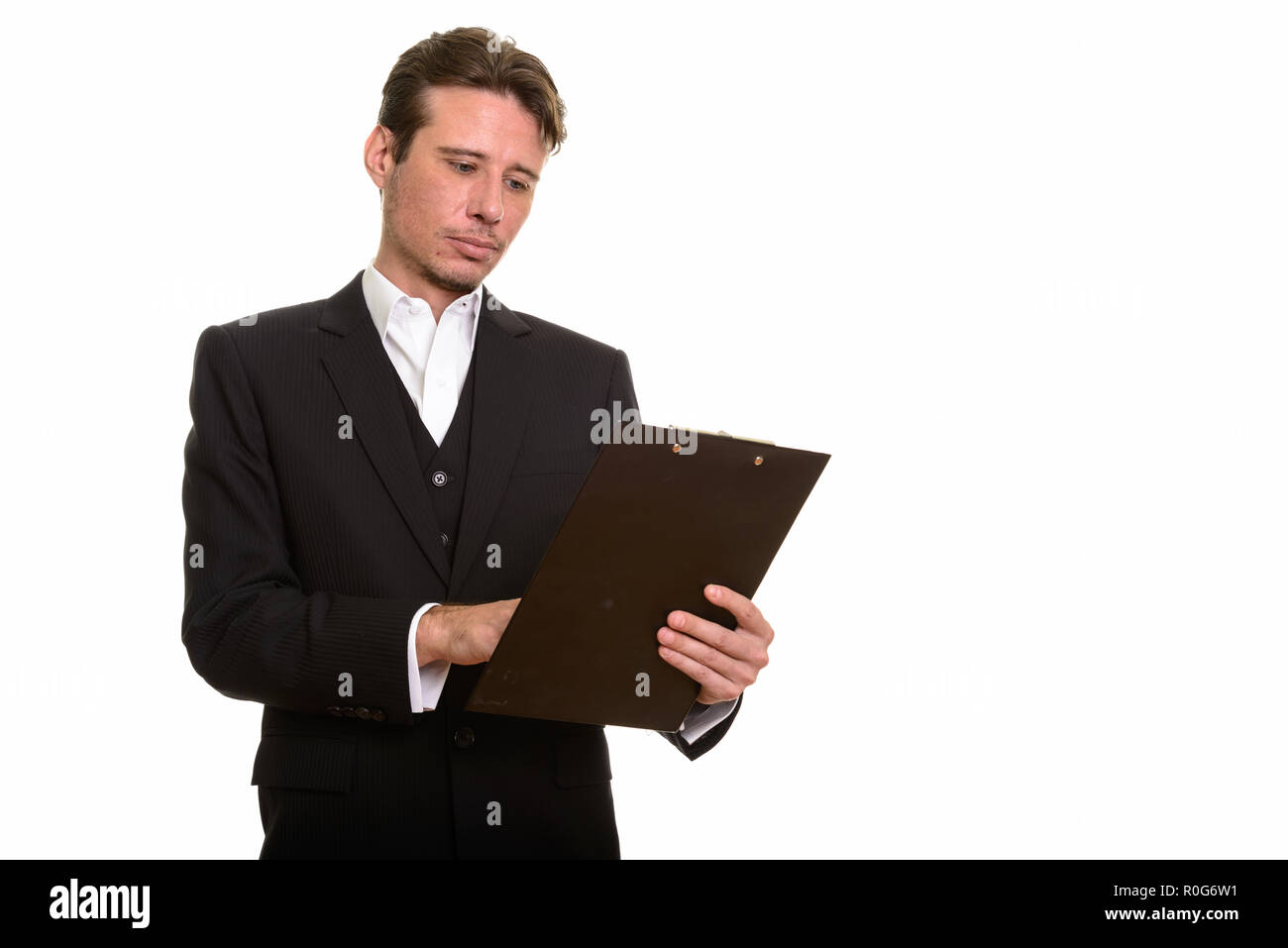 Handsome Caucasian businessman reading clipboard while thinking Stock Photo