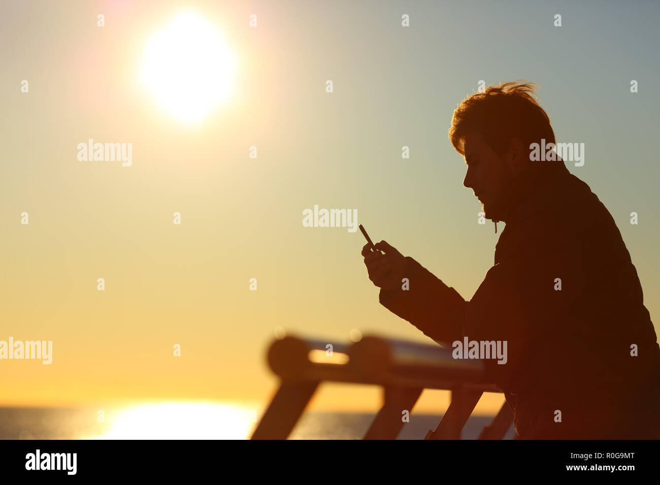Side view portrait of a silhouette of a man using a phone at sunset Stock Photo