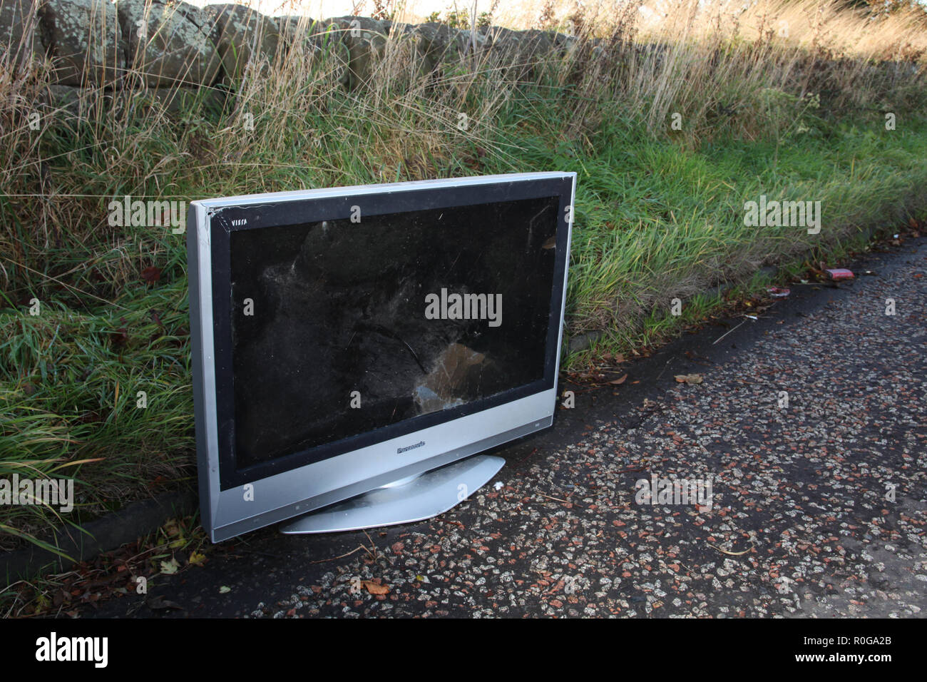 A damaged television set abandoned at the side of the road Stock Photo