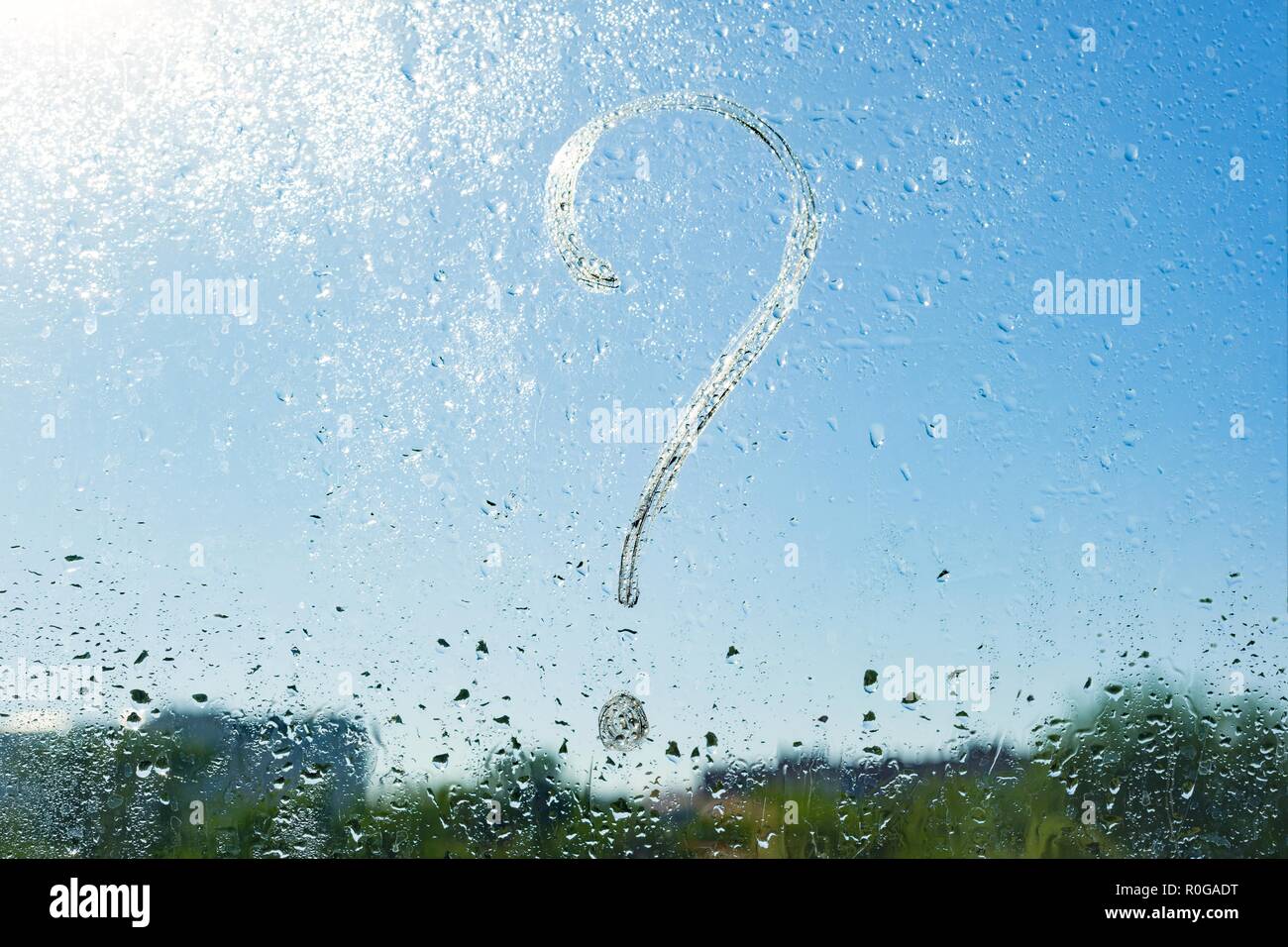 Handwritten question mark on rainy window. Background drop of water on