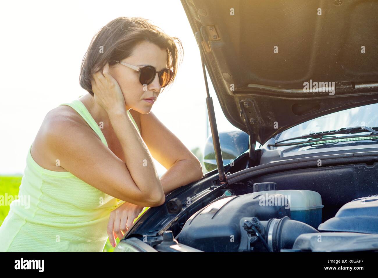 Frustrated woman driver near a broken car. Machine on a country road. The woman has stress Stock Photo