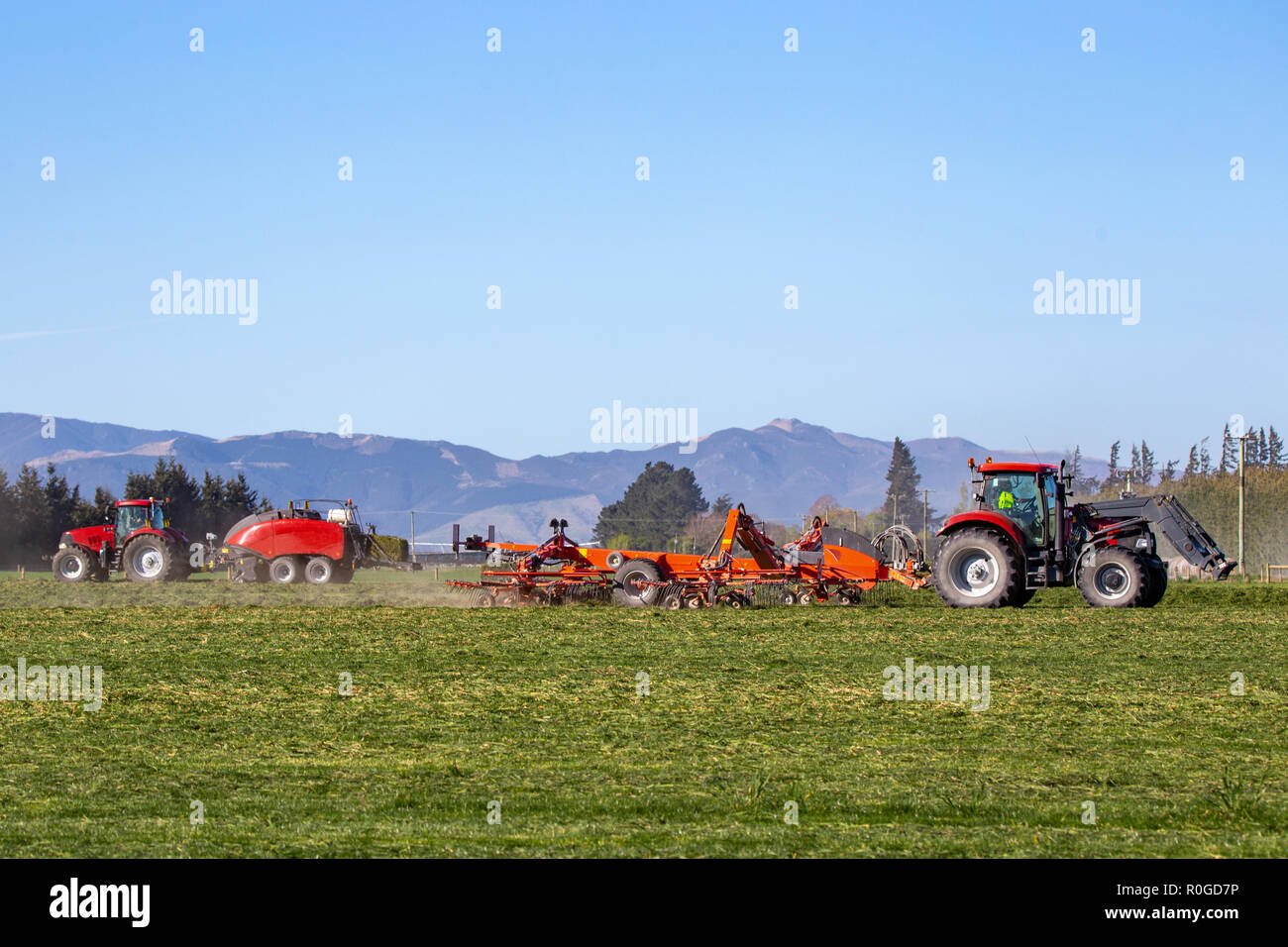 Red farm machinery at work in a rural field in Canterbury, New Zealand