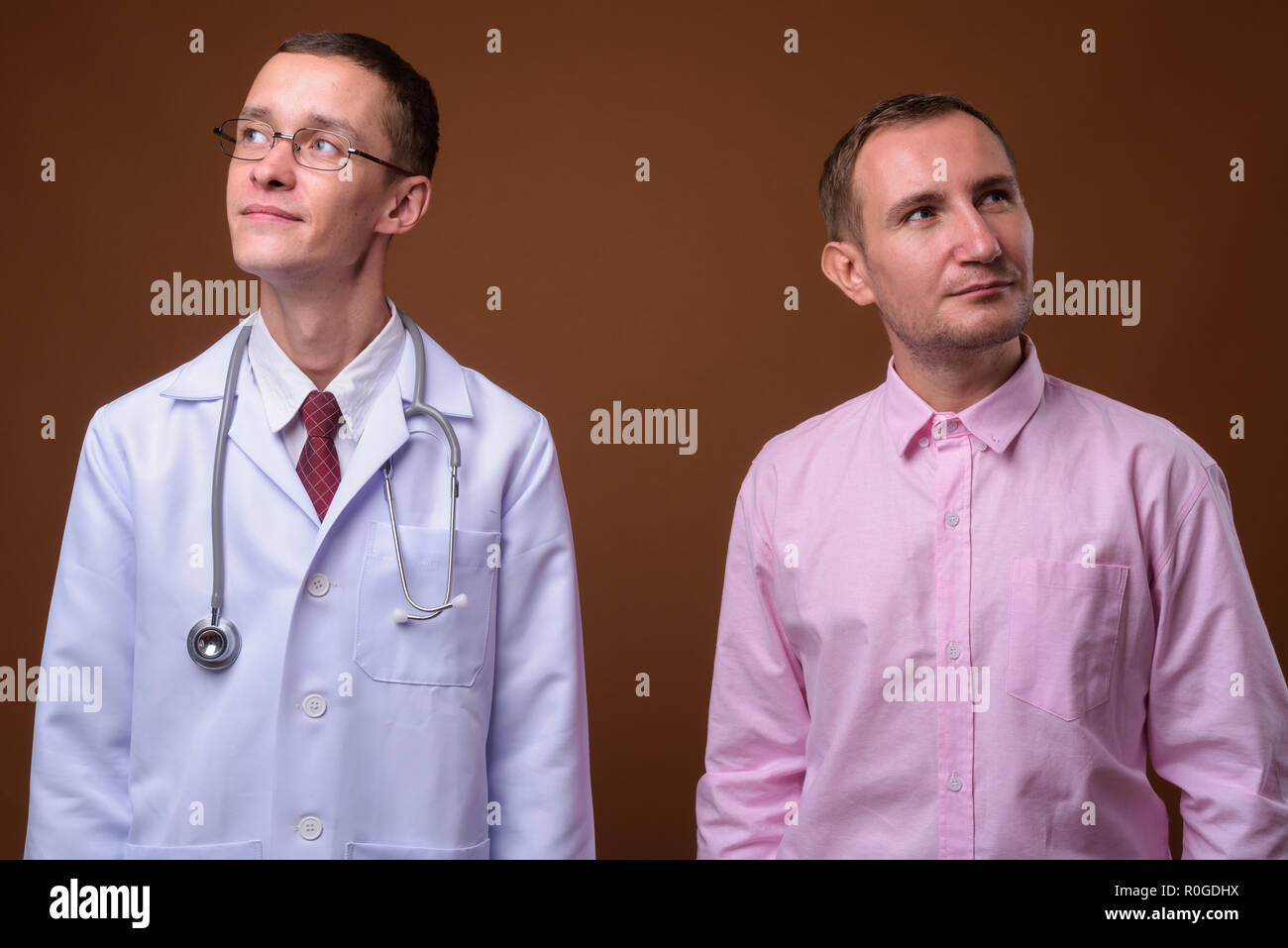 Young man doctor and man patient against brown background Stock Photo