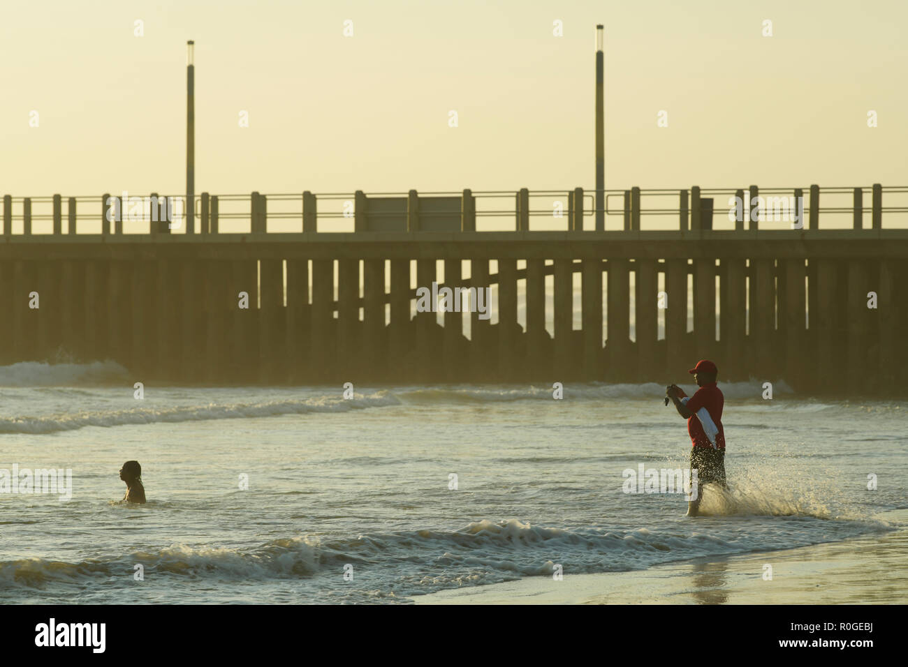 Durban, KwaZulu-Natal, South Africa, single adult man photographing women swimming in surf on a seaside holiday Stock Photo