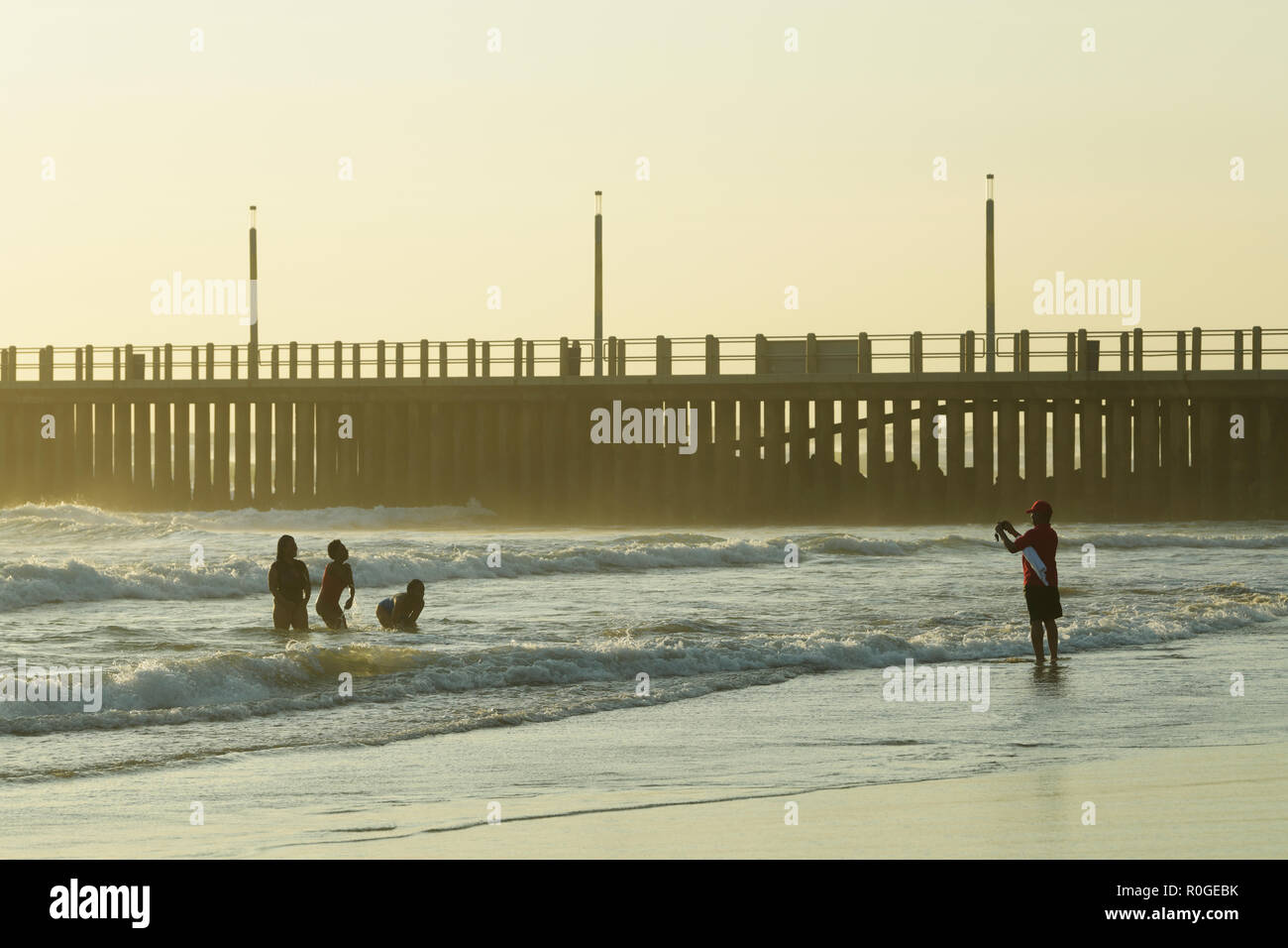 Durban, KwaZulu-Natal, South Africa, single adult male photographing group of three women bathers standing in sea water enjoying seaside holiday Stock Photo