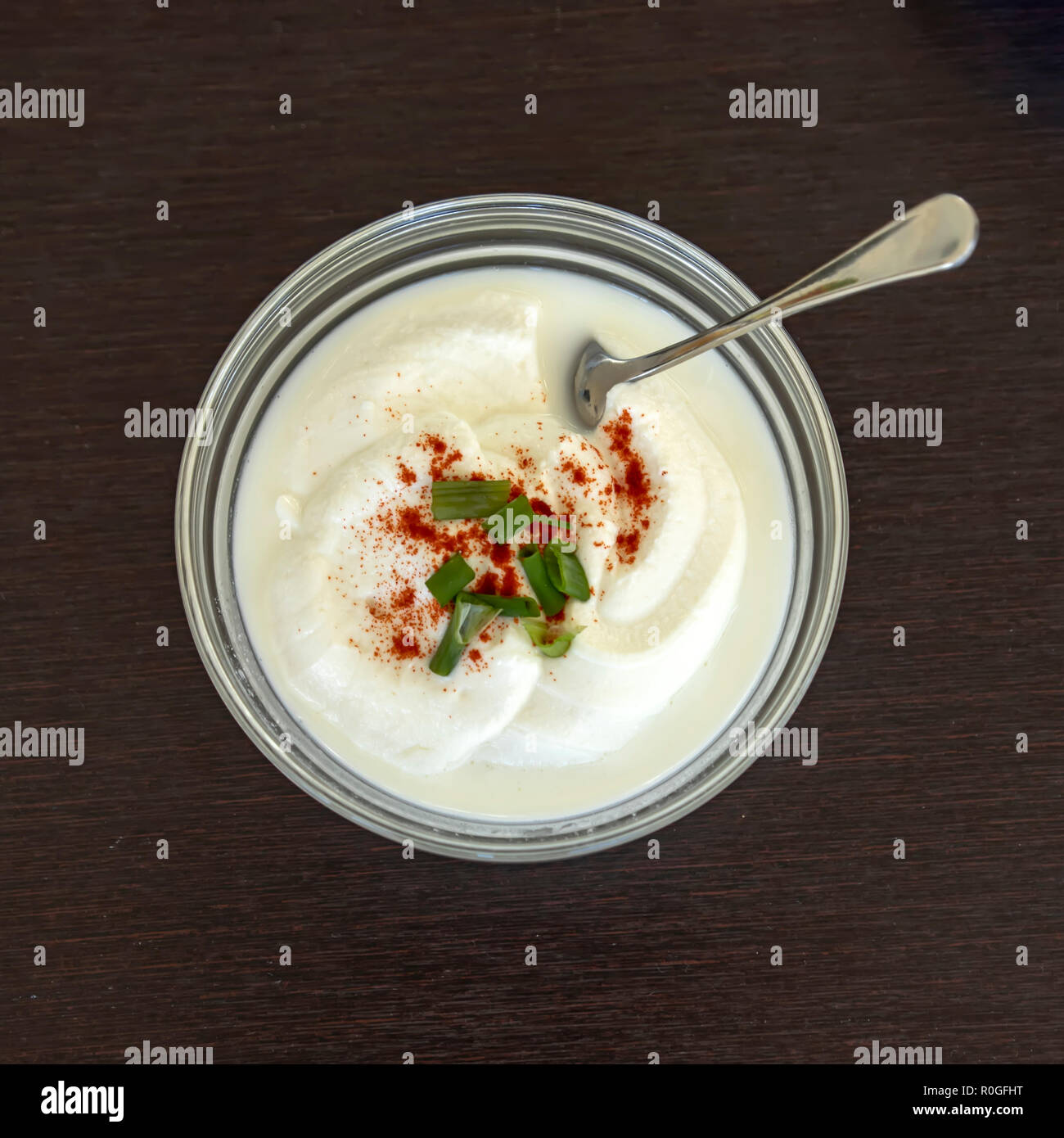 Sour cream in a cup decorated with paprika and green onion sliced. Top view Stock Photo