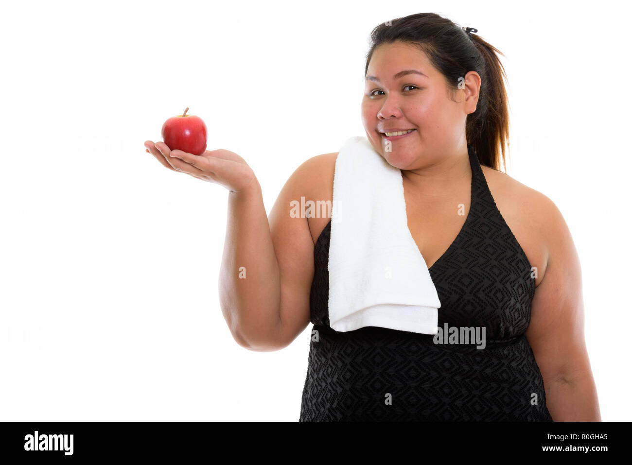 Studio shot of young happy fat Asian woman smiling and holding r Stock Photo