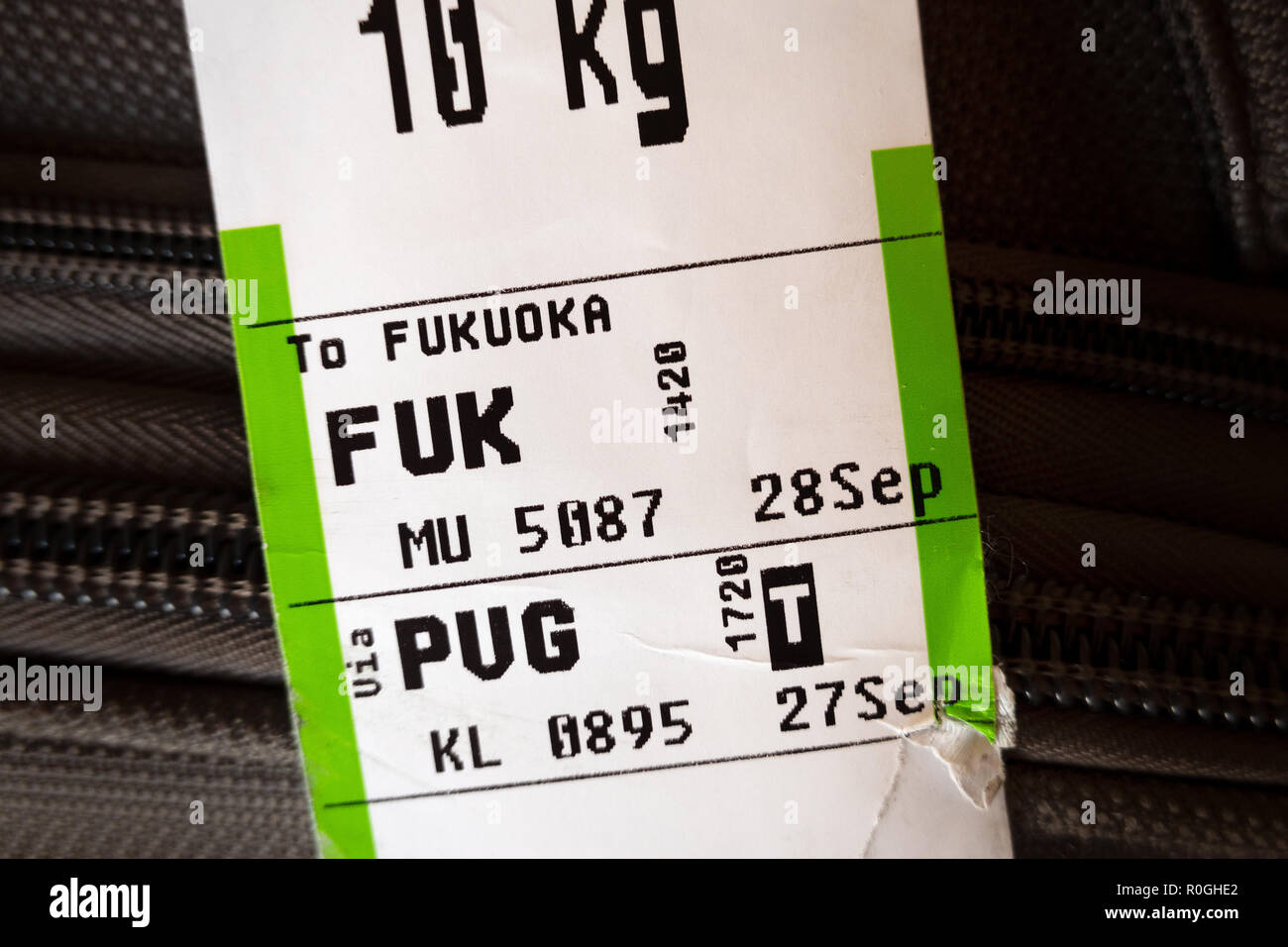 Checked baggage with airline luggage tags showing it's going from Shanghai PVG to Fukuoka FUK airports. Stock Photo