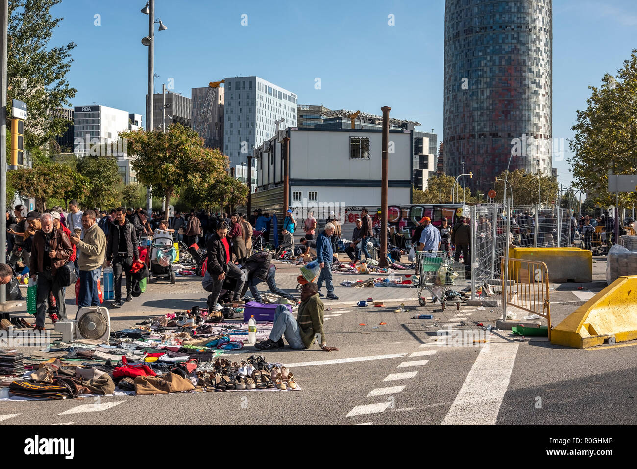 A seller is seen sitting on the ground next to his merchandise in the market of misery. Near the best cultural infrastructures of Barcelona, in the market of survival, most of the products, coming from garbage’s are sold at one or two euros. Continually displaced by the police, the well known 'the market of misery is now placed between cars and large urban renovations of the Plaza de les Glories. Stock Photo