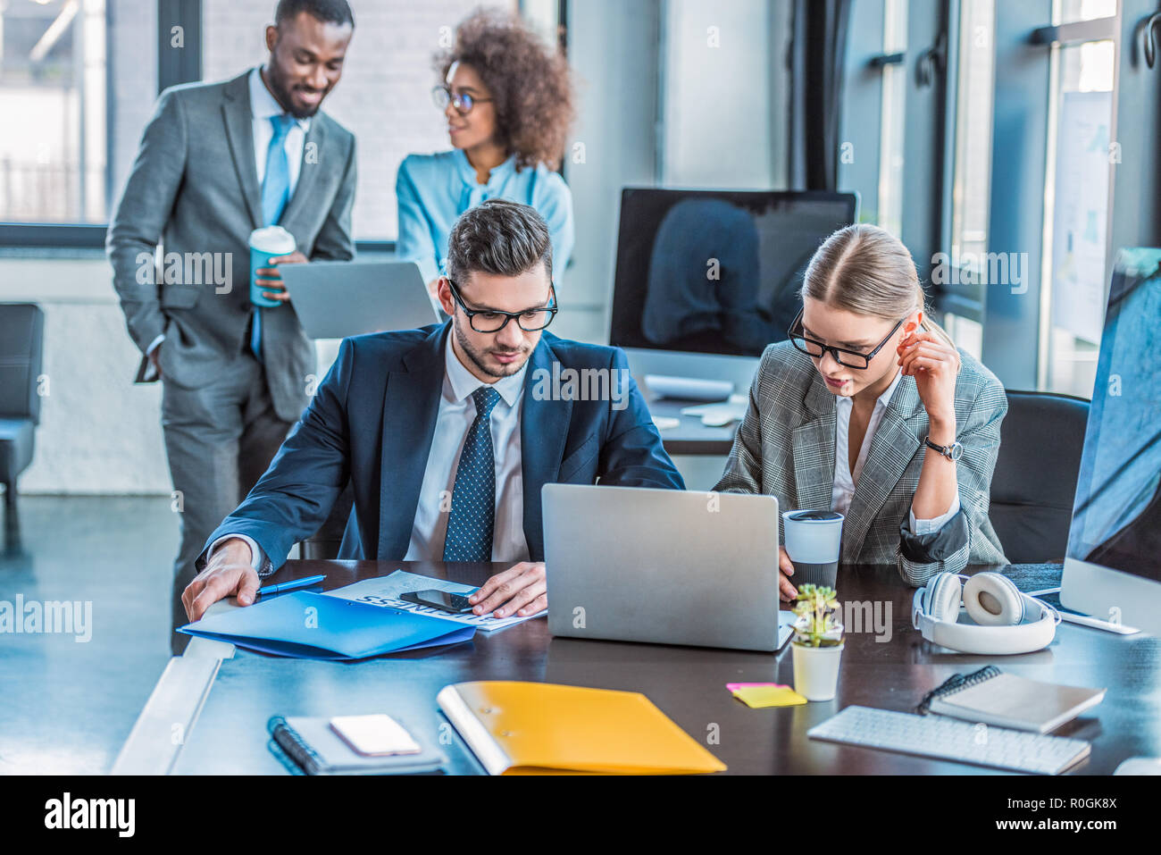 multicultural businesspeople looking at laptops in office Stock Photo