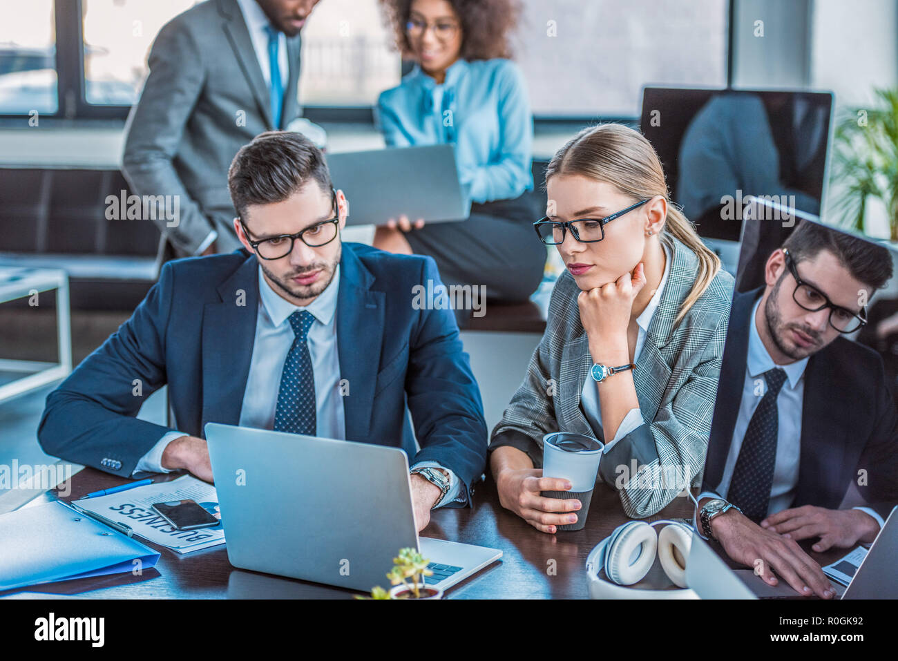multicultural businesspeople looking at laptops in workspace Stock Photo
