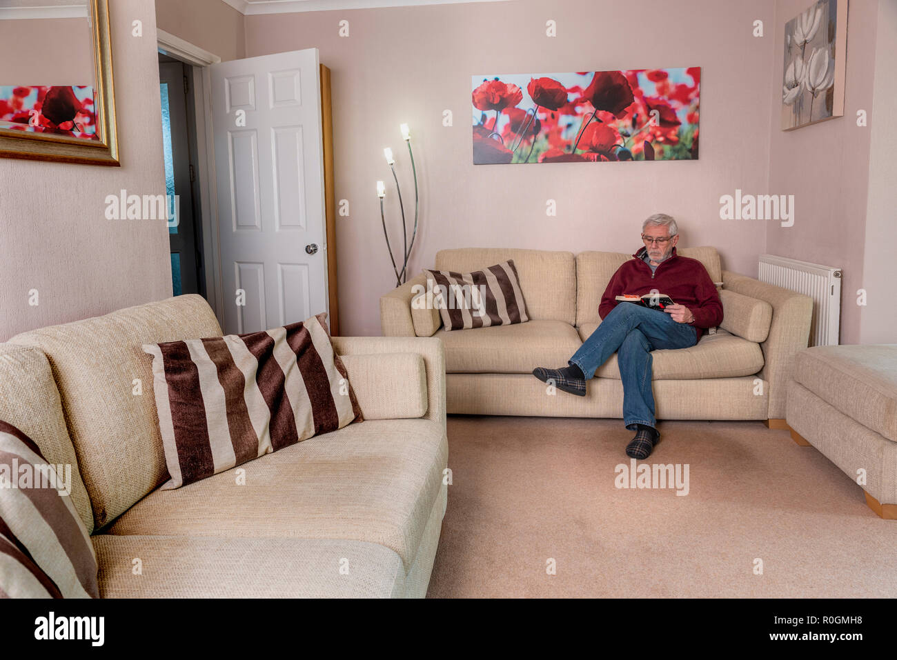 Senior man sitting alone, reading. Home alone loneliness single male. Stock Photo