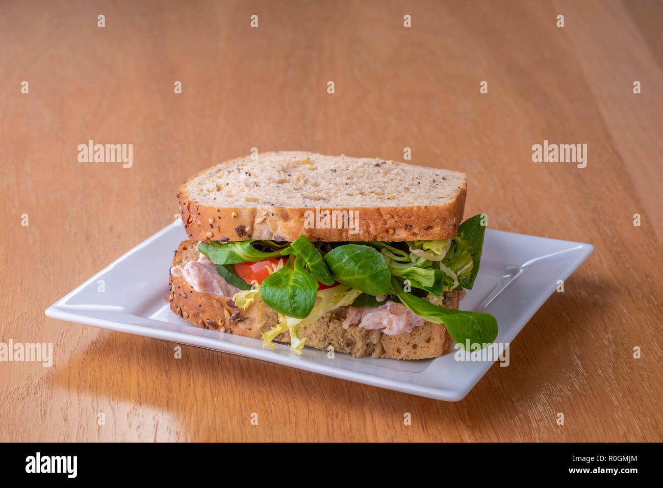 Chicken salad sandwich on a white plate.Turkey lettuce tomato granary bread. Stock Photo