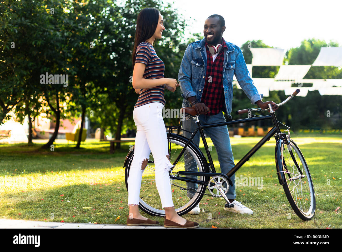 smiling multiracial couple with retro bicycle having conversation in