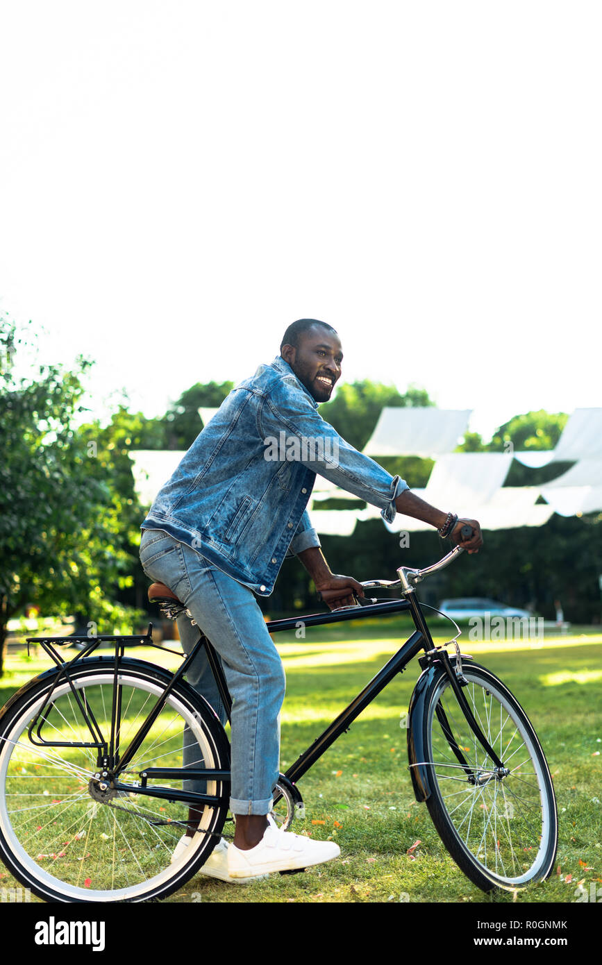 smiling african american man riding retro bicycle in park Stock Photo