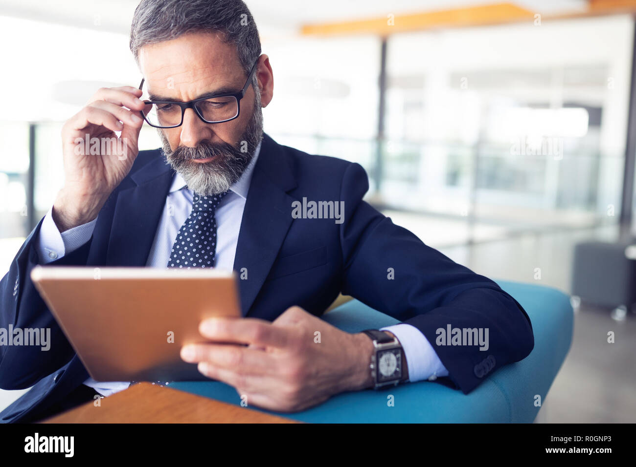 Serious man managing director of big prosperous company is holding touch pad Stock Photo