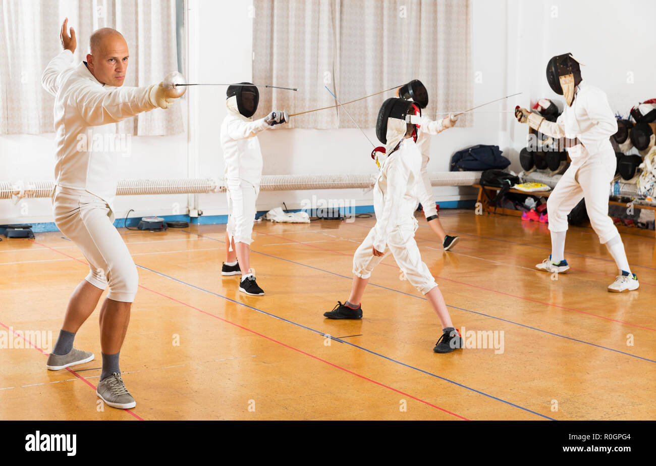 Coach demonstrating to young athletes stances and movements with rapier