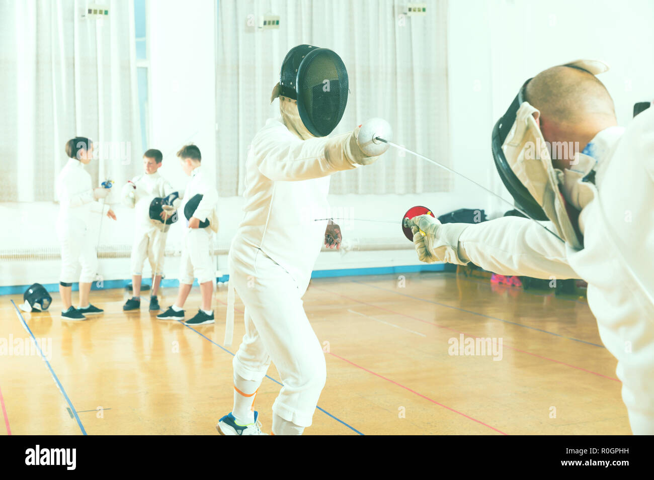Closeup portrait of adult fencer in mask practicing lunge with foil
