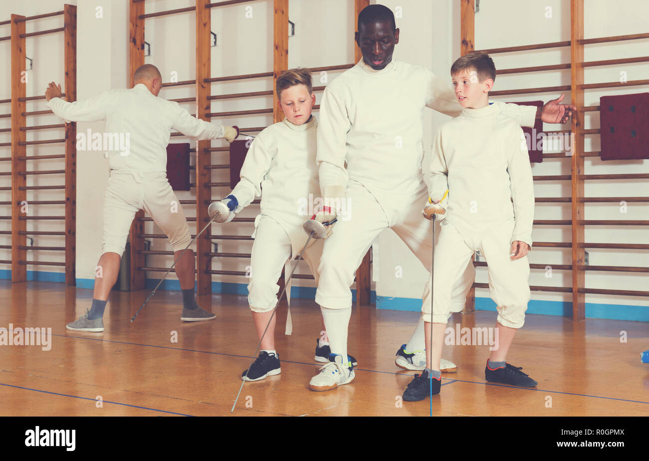 Coach demonstrating to teenage athletes stances and movements with