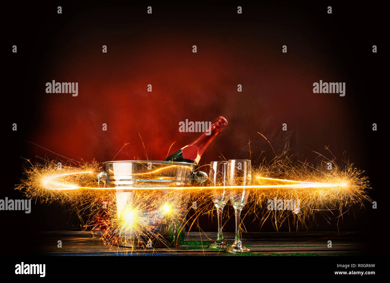 Champagne bottle in ice bucket with two of glasses and fireworks display on bright background Stock Photo