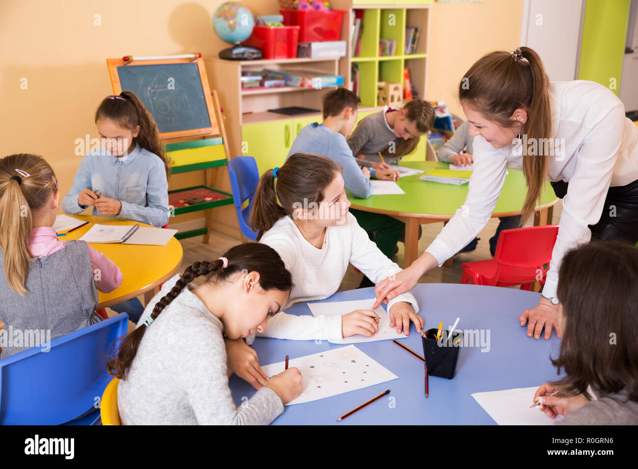 Female teacher helping drawing to group children 9-10 years old Stock ...
