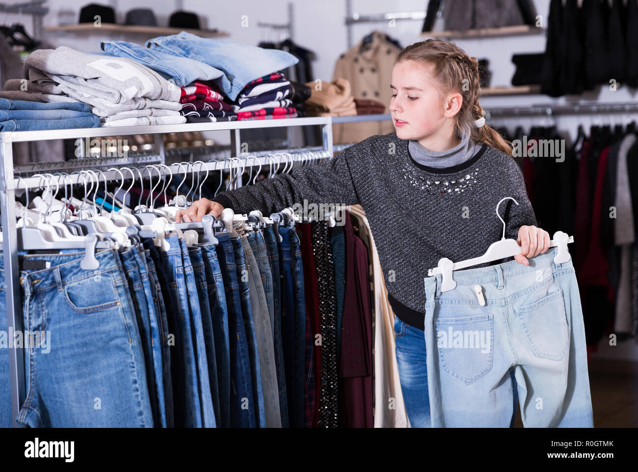 Cute teen girl choosing stylish jeans in clothing store Stock Photo - Alamy