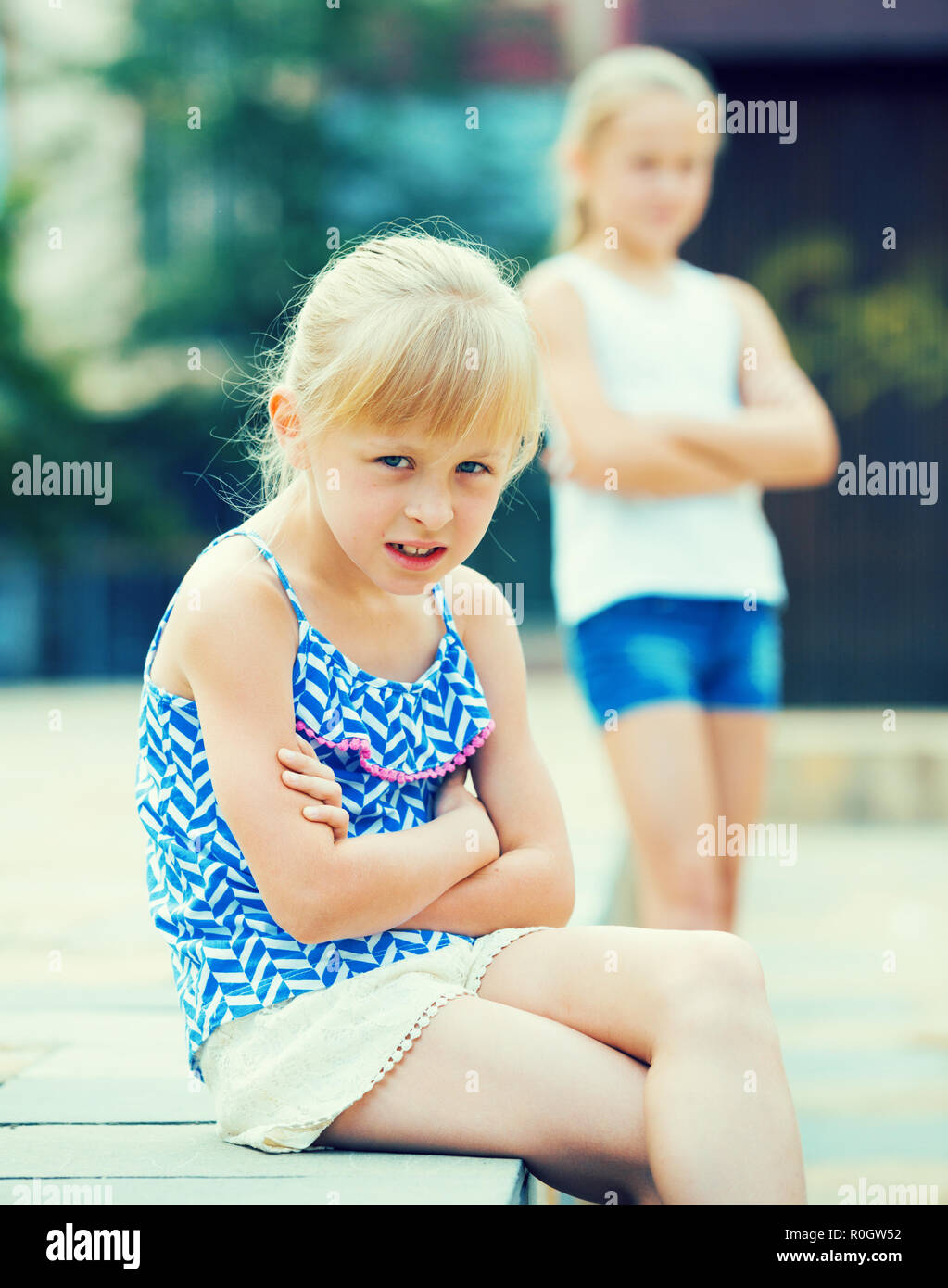 Two offended little girls not talking to each other after quarrel outdoors Stock Photo