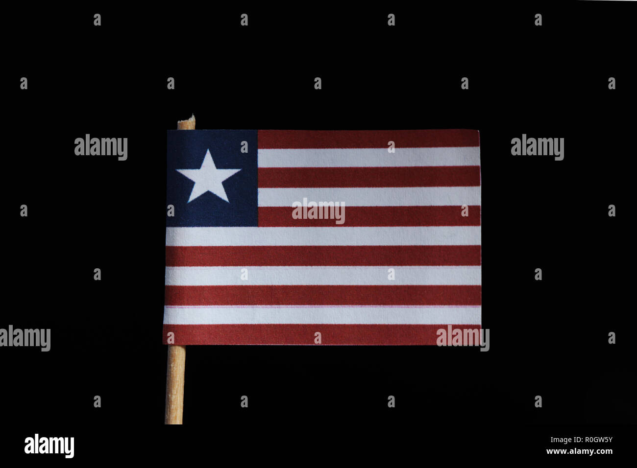 A official flag of Liberia on toothpick on black background. Consists of eleven horizontal stripes alternating red and white, in the canton a white st Stock Photo