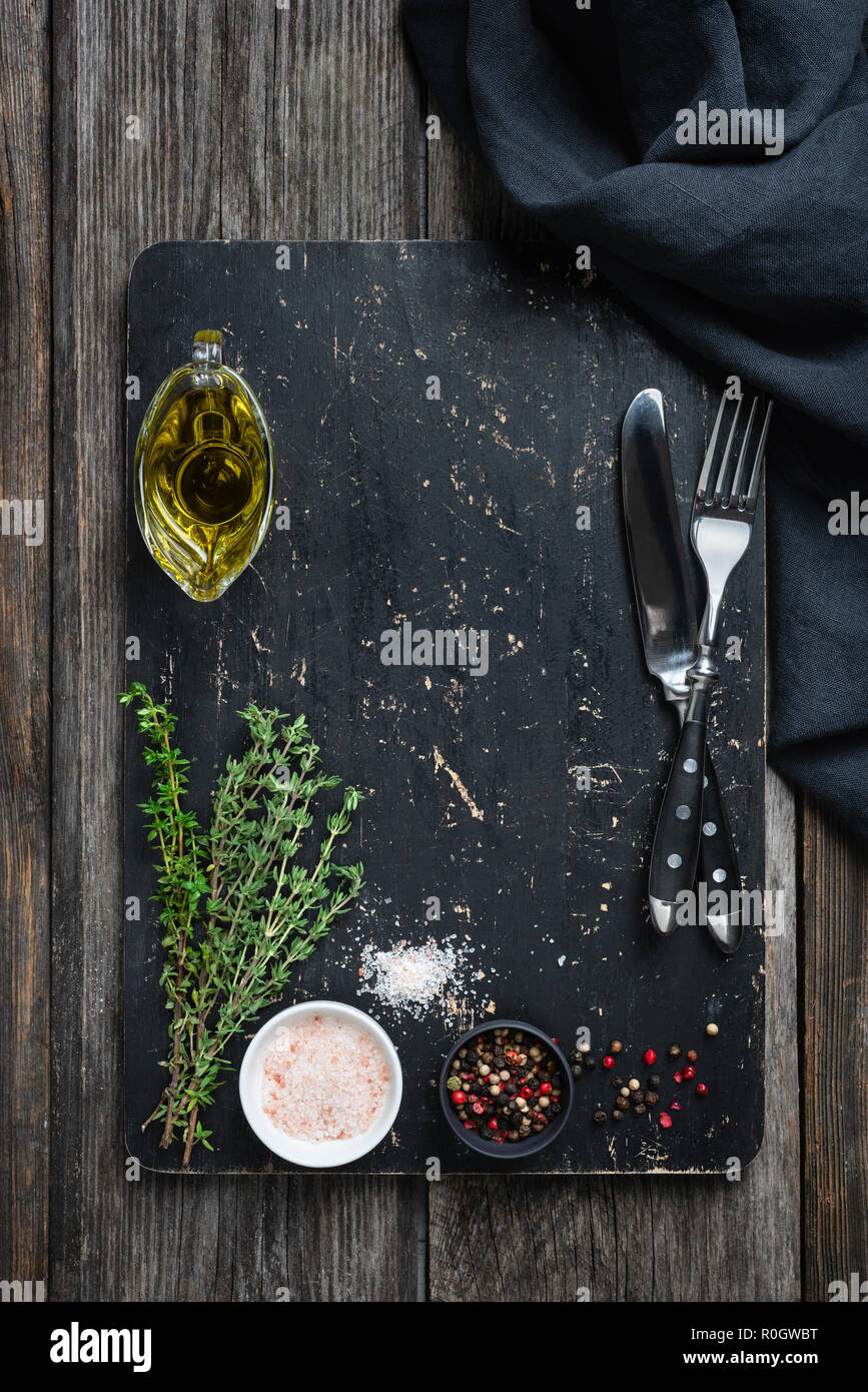 Black cutting board, spices and cutlery with copy space for cooking. Frame composition. Food background menu Stock Photo